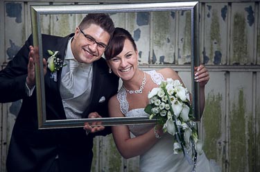 Braut und Bräutigam schauen durch Bilderrahmen beim Fotos machen